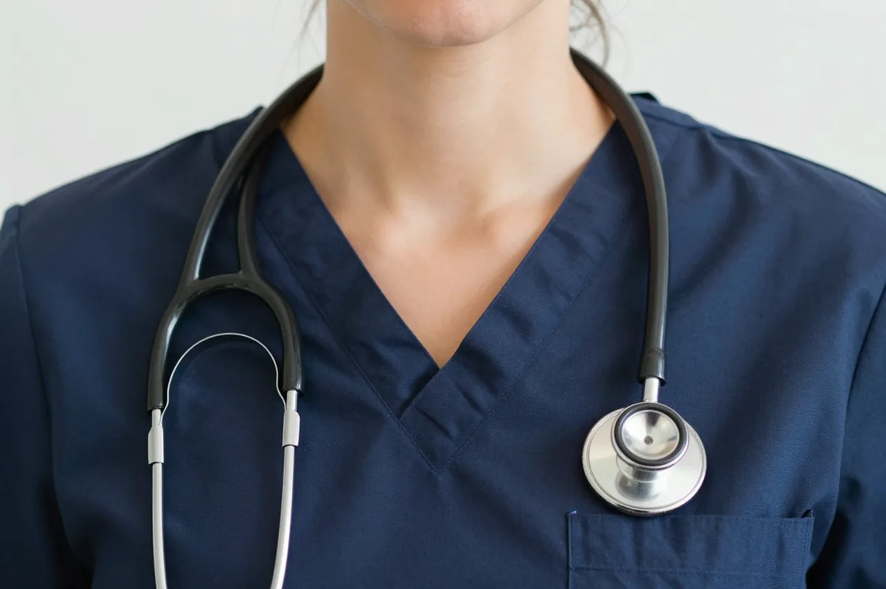 Crop view of a medical worker's neck and torso in navy scrubs with a stethoscope around their neck