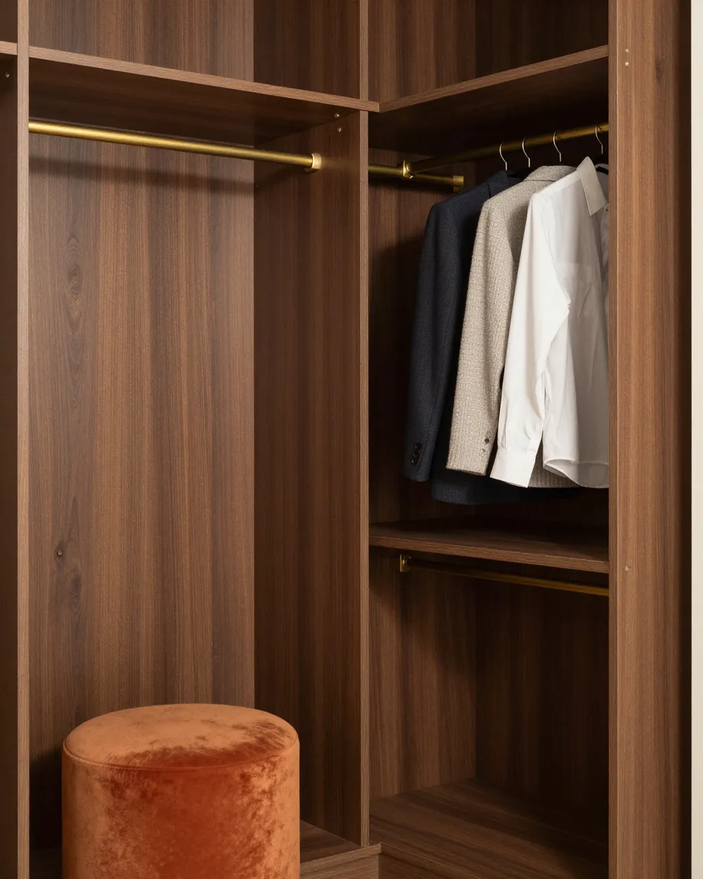 Walnut mid-century walk-in closet with brass hanging rails, hanging garments and an orange velvet stool