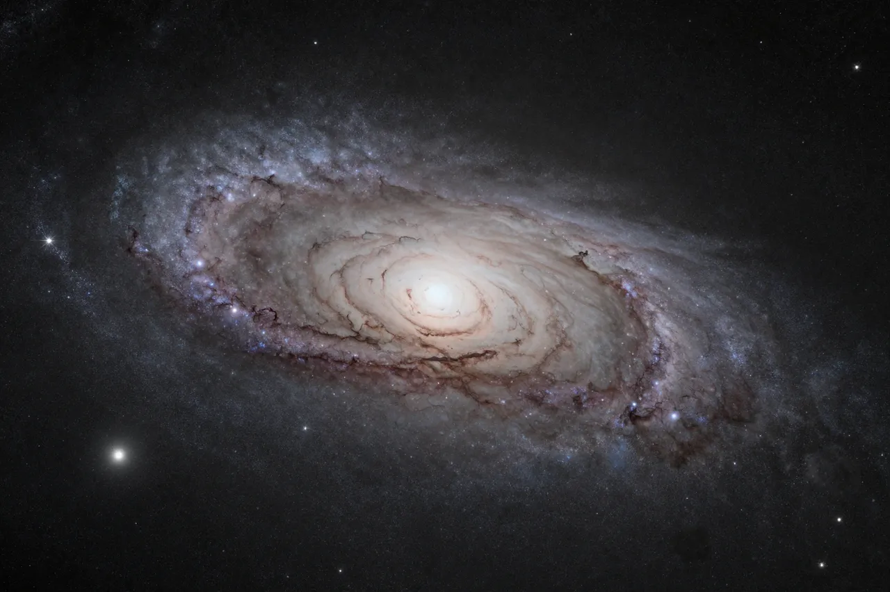 A wide deep exposure view of a spiral galactic core with dark dust lanes against dark space