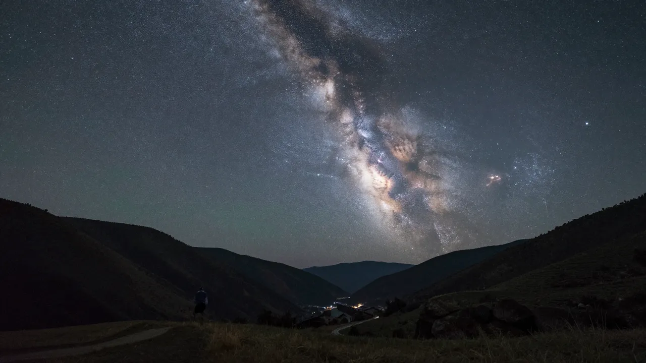 Bright milky way galaxy arches over a quiet mountain valley on a clear dark starry night