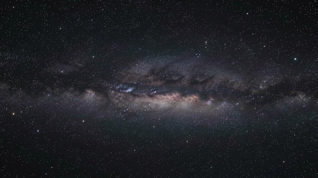 Dense horizontal band of the milky way stretches across a dark star-filled night sky