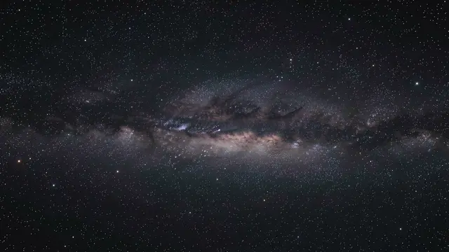 Dense horizontal band of the milky way stretches across a dark star-filled night sky