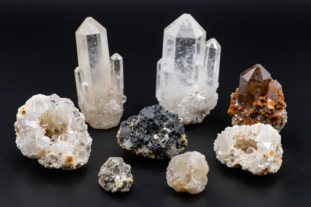 Assorted crystal and mineral specimens arranged neatly on a solid black background