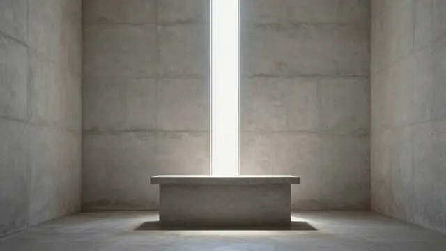 A plain concrete altar sits in a bare chapel with a vertical shaft of light falling onto its surface