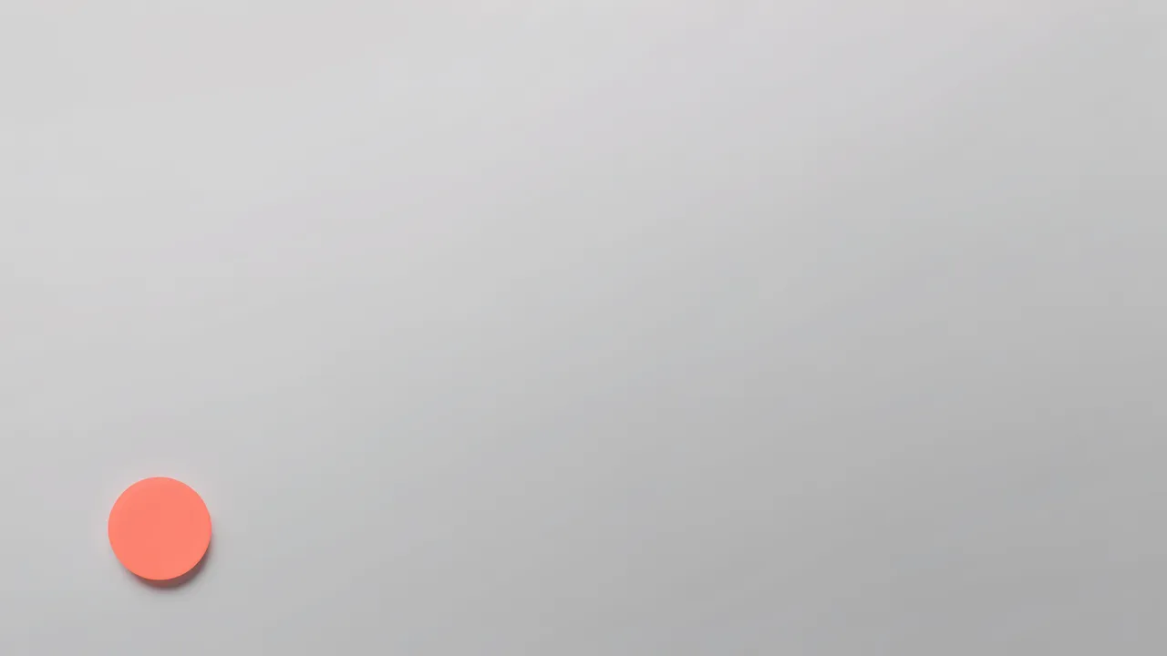 A soft pale gray gradient desktop wallpaper with a small solid coral circle resting low on the left side.