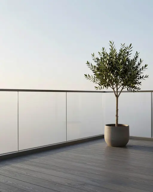 A single potted olive tree sits on a gray wood balcony with frosted glass railing at soft sunrise
