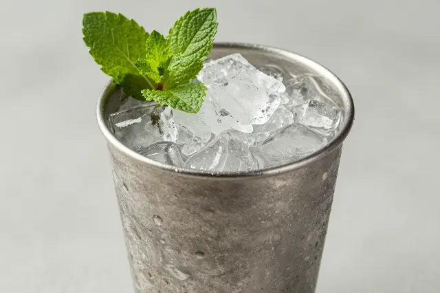 Frosted silver mint julep cup filled with ice and topped with a fresh mint sprig