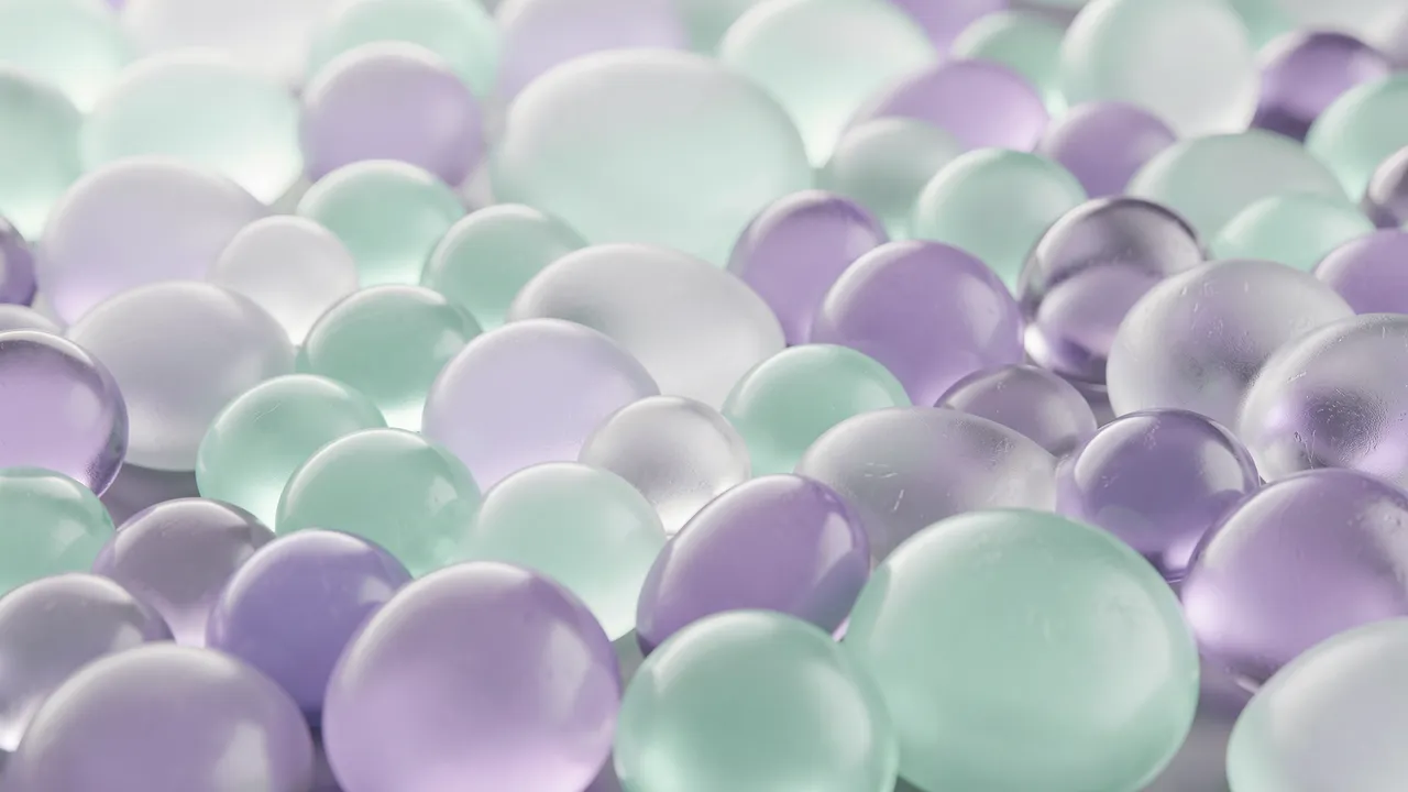 Soft frosted mint and lilac rounded glass pebbles catch gentle diffused light in a dense arrangement.