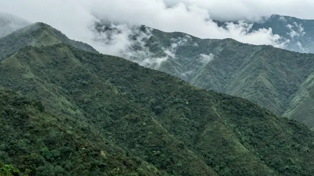Dense green mountain ranges with wispy clouds drifting between the ridges after rainfall