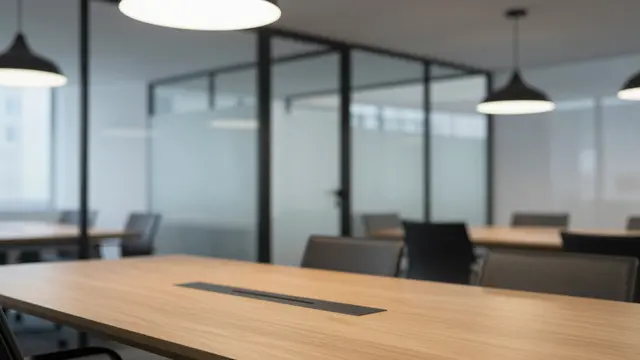 Softly blurred view of a modern empty office with glass walls, wooden meeting table and pendant lights