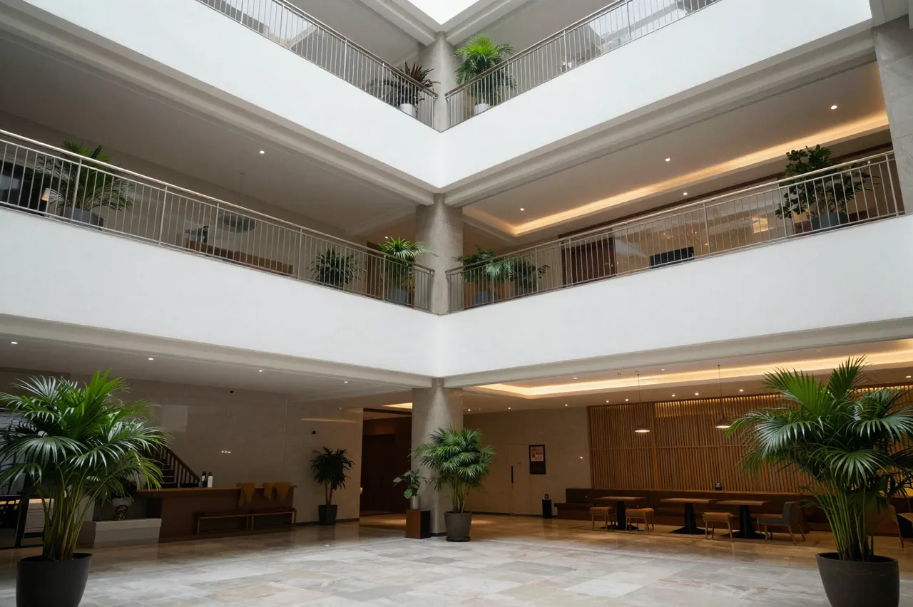 Spacious multi-level hotel lobby with potted plants, polished marble flooring and warm recessed lighting