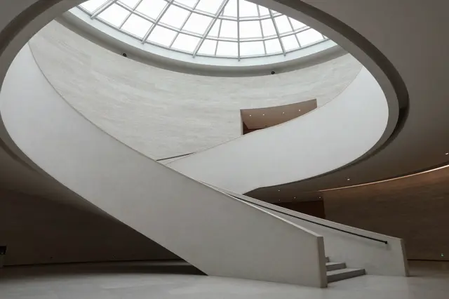 Curved concrete museum atrium with a glass domed skylight overhead