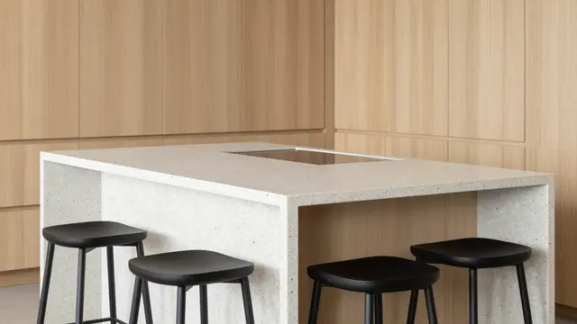 Minimalist kitchen with a waterfall edge terrazzo island, black stools and pale oak cabinetry