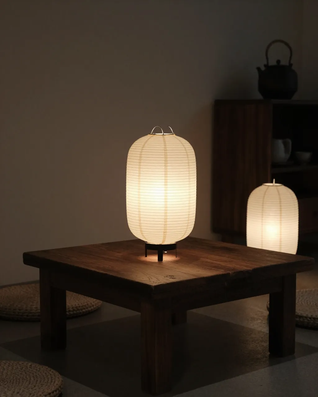 Glowing paper lanterns sit on a low wooden table in a dim calm tea room interior