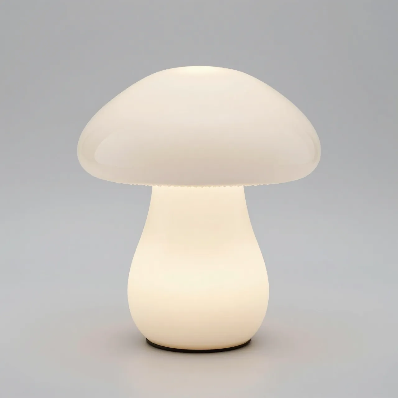 Glowing white mushroom shaped glass table lamp against a light gray studio background