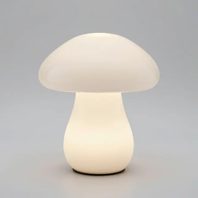 Glowing white mushroom shaped glass table lamp against a light gray studio background