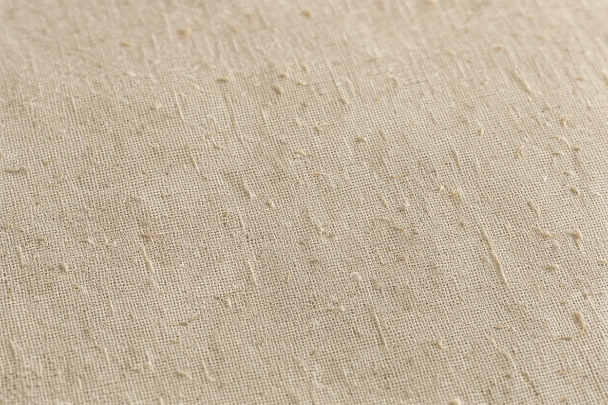 Close-up full frame of textured light beige linen fabric with visible weave and slub details