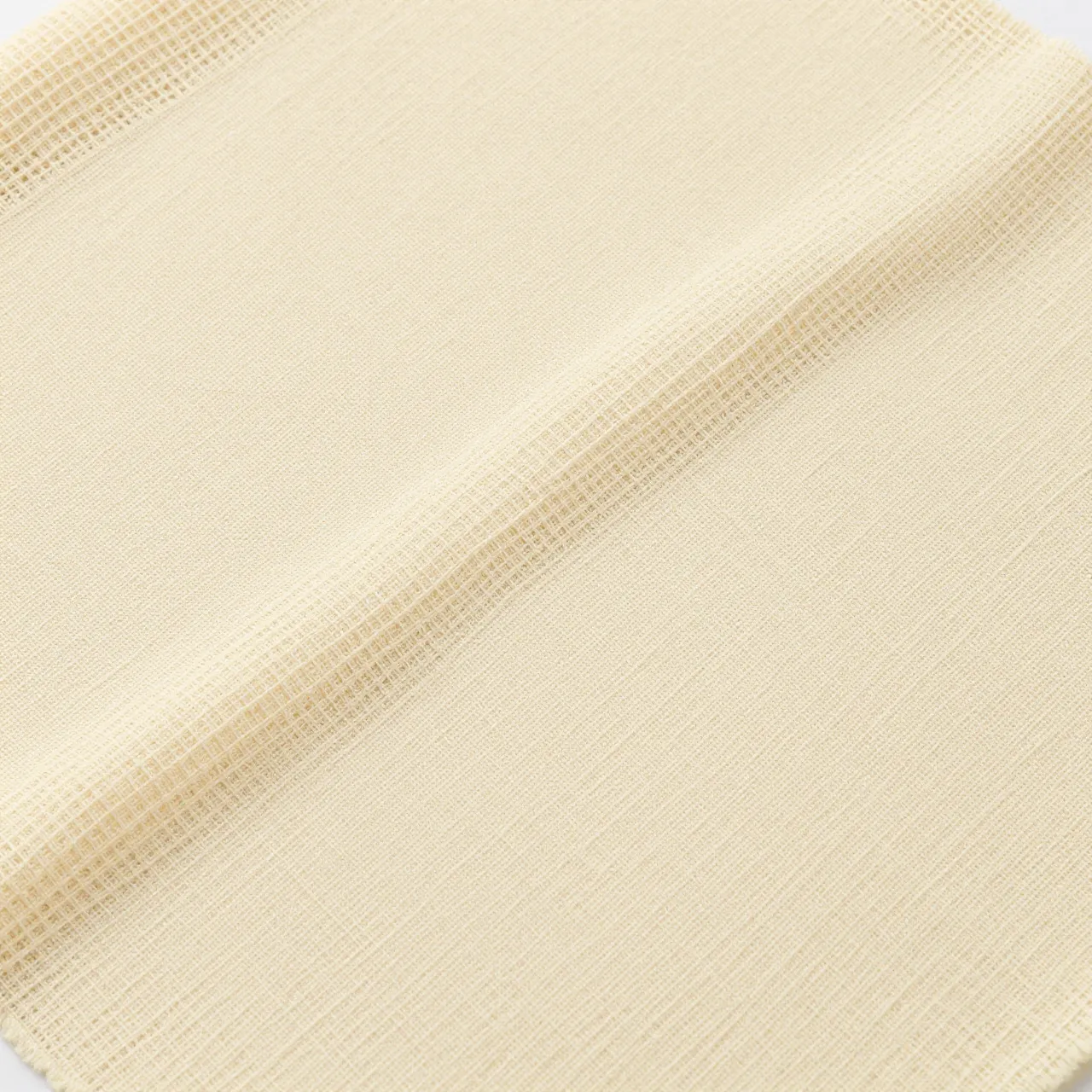Full frame close-up of loosely woven pale beige cheesecloth fabric with a soft diagonal fold
