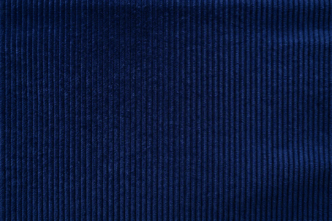 Full frame close up of deep navy fine wale corduroy fabric with vertical ribbed texture