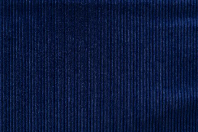 Full frame close up of deep navy fine wale corduroy fabric with vertical ribbed texture