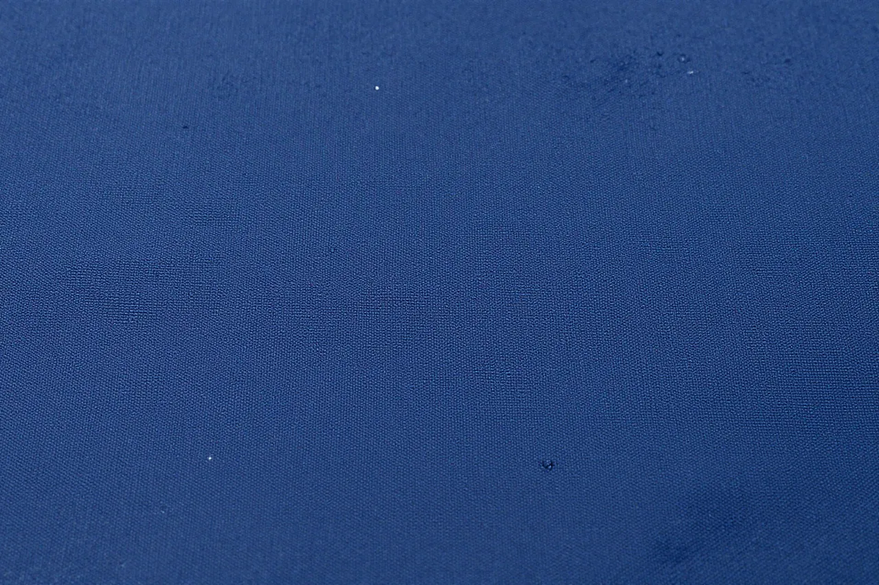 Full frame close-up of navy woven nylon waterproof fabric with small scattered water droplets