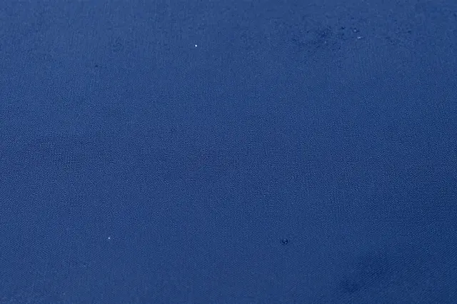 Full frame close-up of navy woven nylon waterproof fabric with small scattered water droplets