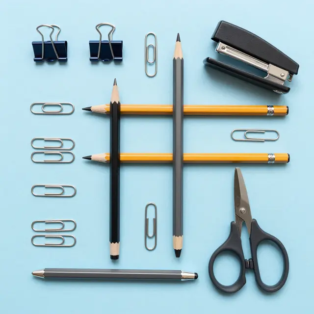 Top-down flat lay arrangement of office supplies neatly aligned on a pale blue background