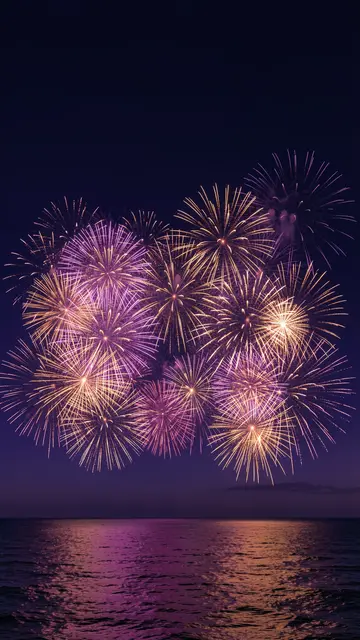 Purple and gold fireworks burst over a dark calm sea, with empty dark sky at the top of the frame.