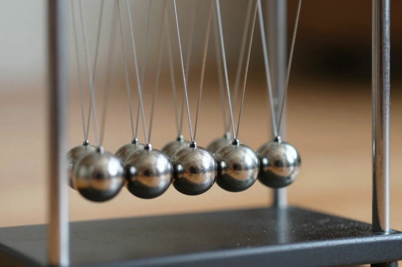 Close up view of a moving Newton's cradle with shiny steel balls and blurred motion on the outermost spheres