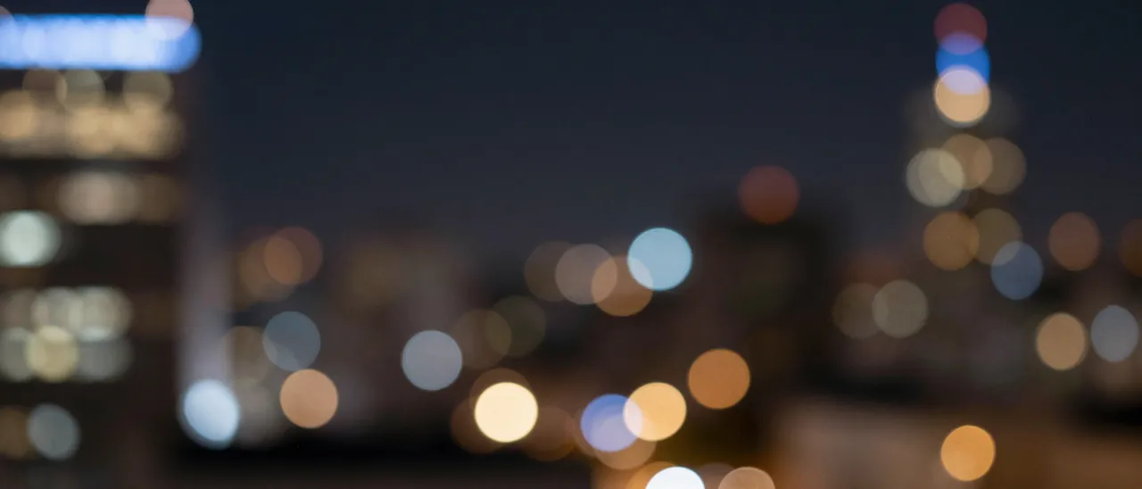 Blurred soft circular blue and gold city light bokeh sits against a dark night sky with empty central copy space.
