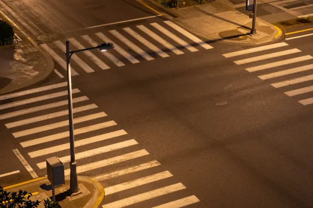 Aerial view of empty crosswalks at a street intersection lit by warm streetlamp light after dark