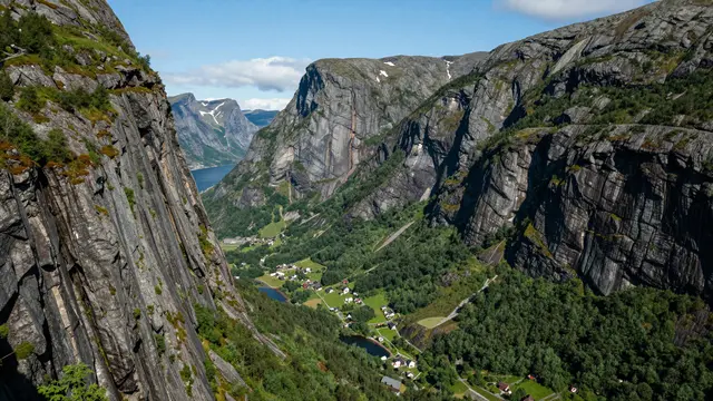 High angle view of a steep rocky fjord valley with a small village under a clear blue sky