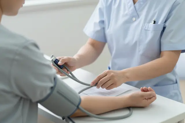 A nurse takes an adult patient's blood pressure during a clinic appointment.