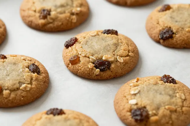 Fresh oatmeal raisin cookies arranged on a sheet of white parchment paper