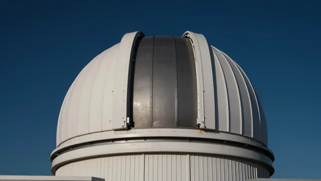 A white and metal observatory dome stands against a deep clear blue sky