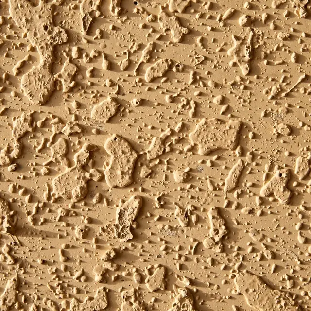 Full frame close-up of textured orange peel drywall lit by soft raking warm light