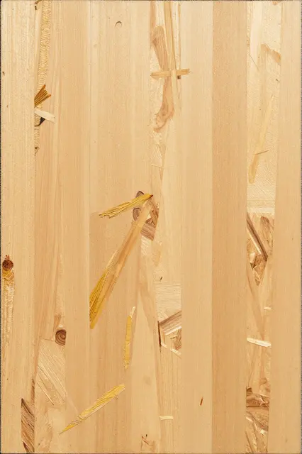 Full frame close-up of light oriented strand board showing pressed golden wood flakes under even flat lighting
