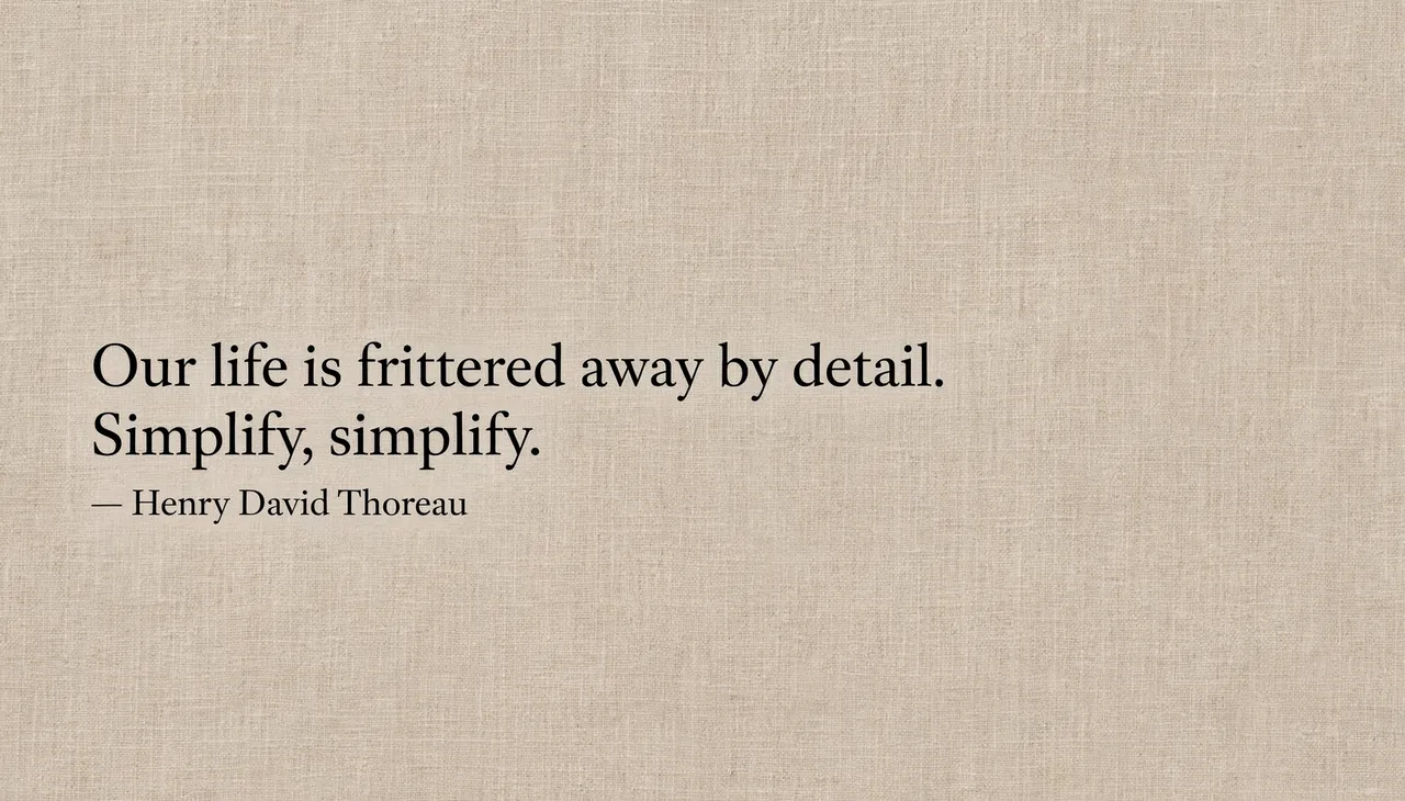 Black serif Thoreau quote set left on a warm beige linen textured desktop wallpaper reading "Our life is frittered away by
