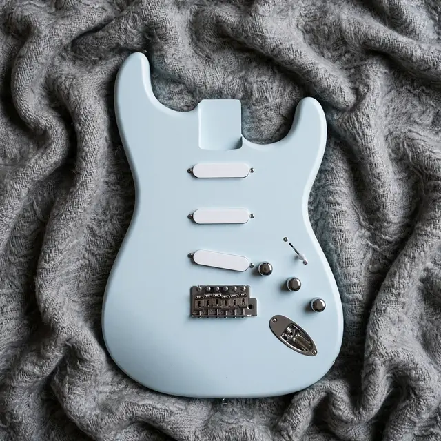 Overhead view of a pale light blue electric guitar body resting on a textured gray wool blanket
