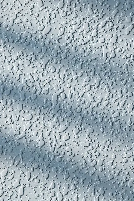 Full frame close-up of pale blue matte knockdown wall texture with soft raking light highlighting small splatter dots