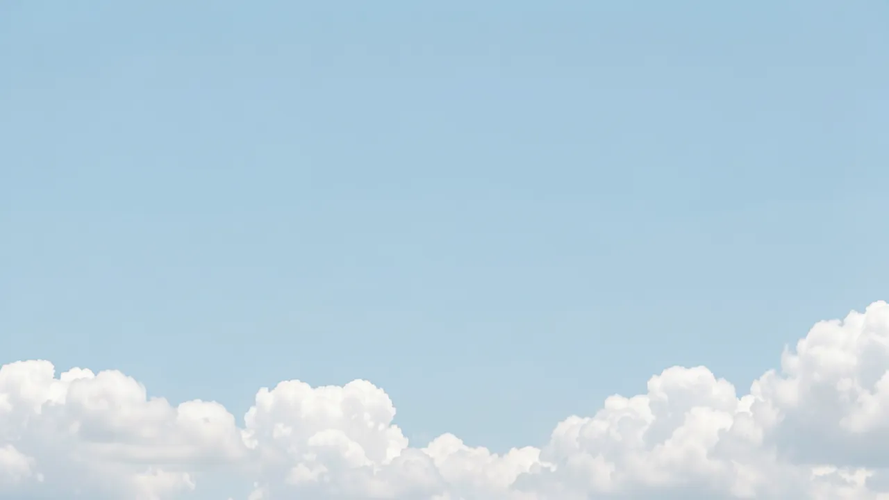 Calm pale blue sky with fluffy white cumulus clouds running along the bottom edge of the frame
