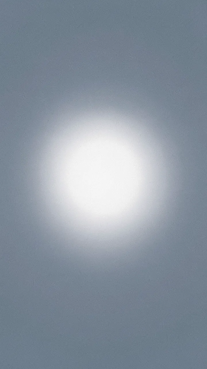 A grainy slate blue-gray vertical gradient with a soft glowing pale white halo centered in the frame