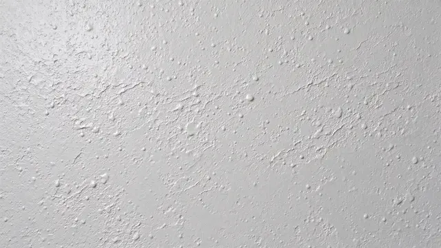 Full frame close-up of pebbly pale gray orange peel ceiling plaster texture