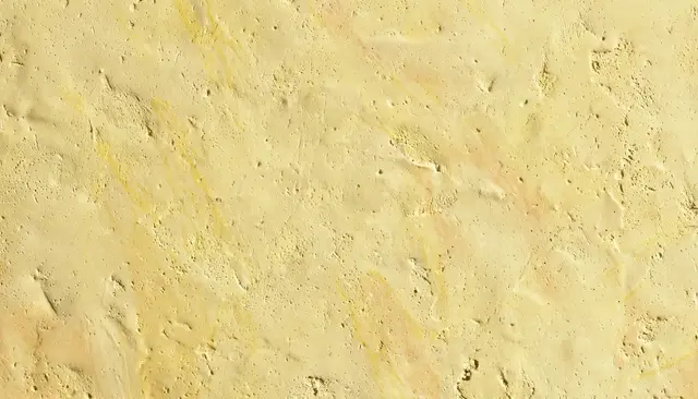 Full frame close-up of a sun-warmed pale yellow matte plaster wall with subtle streaks and fine pits