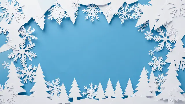 White paper cut snowflakes and pine trees form a decorative frame around an empty ice blue center