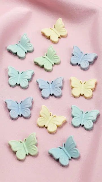 Top view of scattered pastel butterfly hair clips resting on soft pink satin fabric