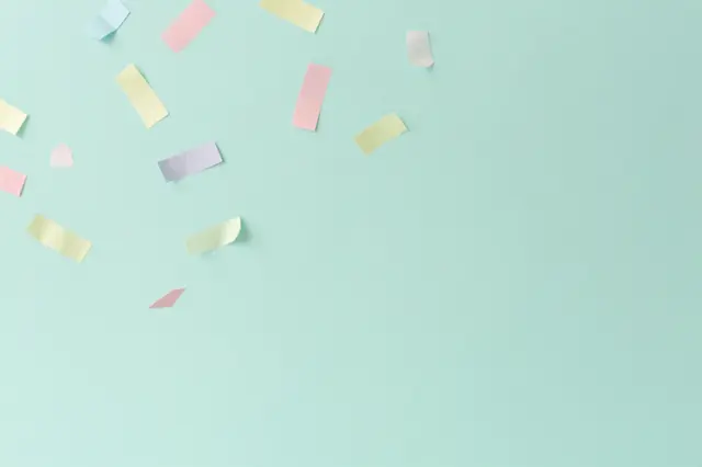 Delicate pastel paper confetti drifts across a smooth solid mint green background with empty copy space
