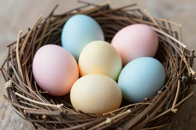 Soft pastel pink, blue and yellow Easter eggs rest inside a twig bird nest.