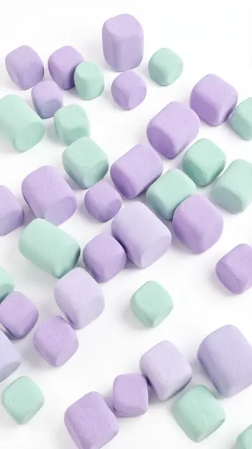 Soft rounded lilac and mint marshmallow-style cubes scattered across a plain white background