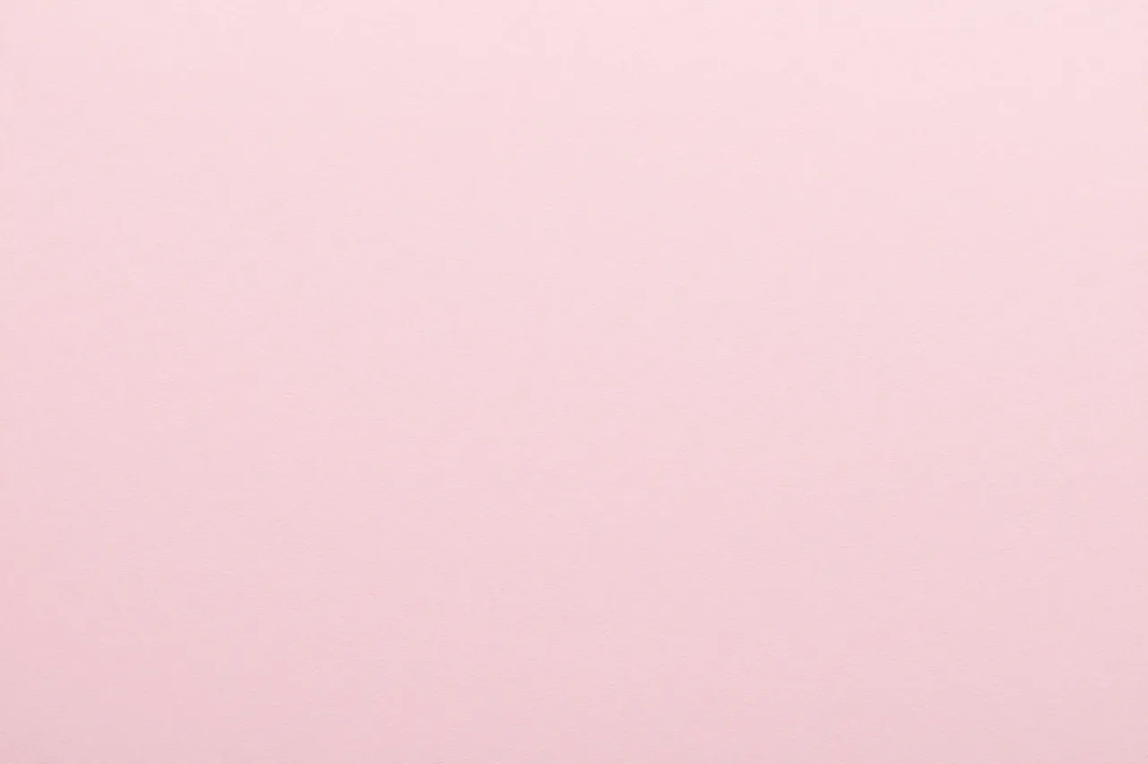 Full frame close-up of smooth soft blush pink paper with a faint fine felted surface nap.